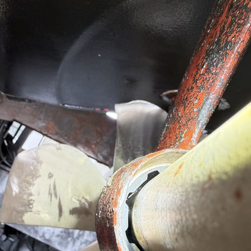 Close view of a propeller blade beside a corroded shaft strut and its bearing.