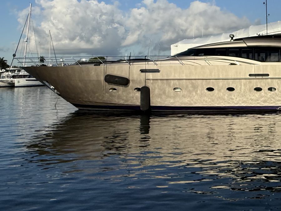 The bow of a large motor yacht lying at a dock, where the vessel's hull meets the water.