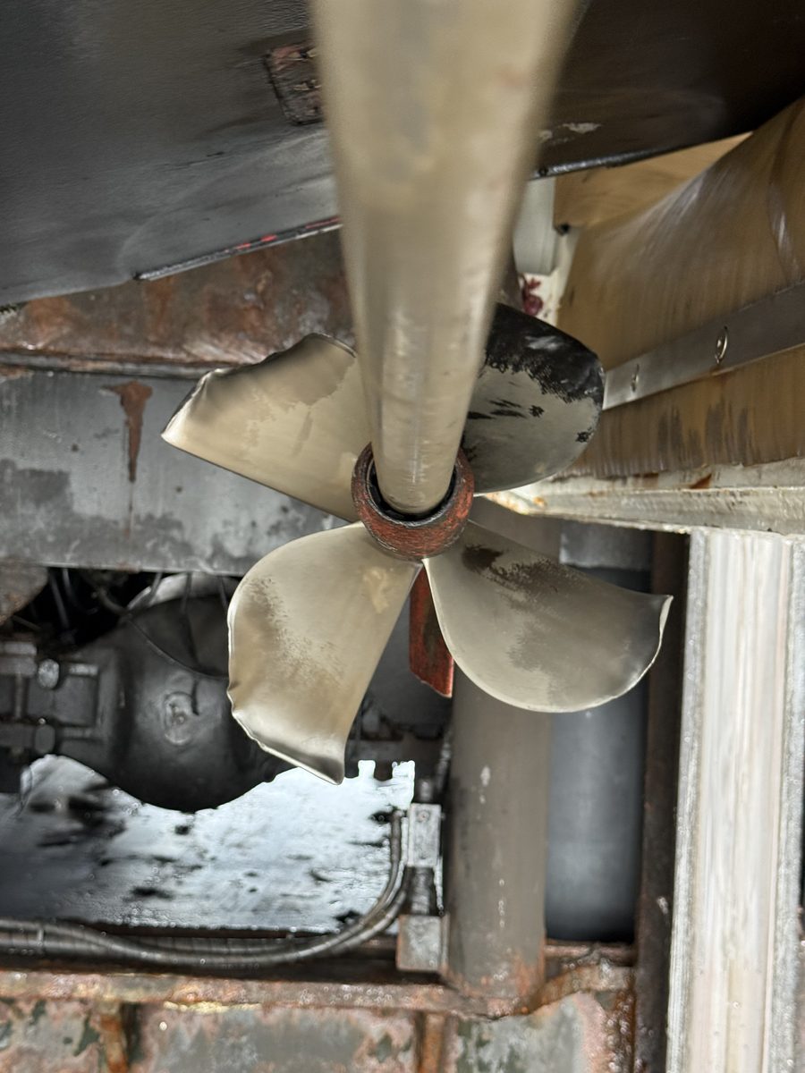 A propeller and shaft beneath a hauled vessel, blade tips visibly bent.
